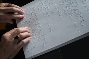Mains sur une page de texte en braille
